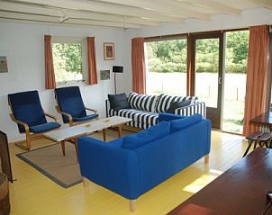 Lichte woonkamer van vakantiehuis Krekel in Nes, Ameland met comfortabele banken en uitzicht op de natuur van de Waddeneilanden.