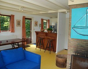 Gezellige eet- en zithoek in vakantiehuis Krekel, Nes, Ameland met houten interieur en uitzicht op de natuur van de Waddeneilanden.