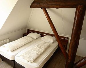 Slaapkamer met houten balken in appartementenboerderij de Jong, Nes, Ameland.