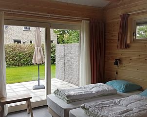 Lichte slaapkamer met uitzicht in Ascona vakantiehuis, Nes, Ameland, biedt rust en ontspanning op de Waddeneilanden.