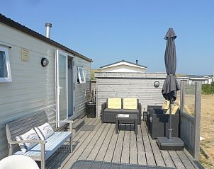 Gezellige zithoek op het terras van de Cirkel chalet in Nes, Ameland, met comfortabele tuinmeubelen en parasol.
