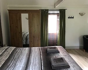Comfortabele slaapkamer in Sturrishuus appartement in Varsseveld, met houten kast en gordijnen.