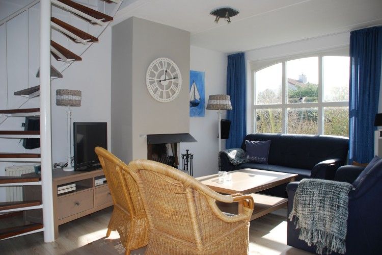 Cozy living room of Krim 661 with sauna, Stuha, and BBQ, a bungalow in De Cocksdorp, Texel, with comfortable seating area and fireplace.