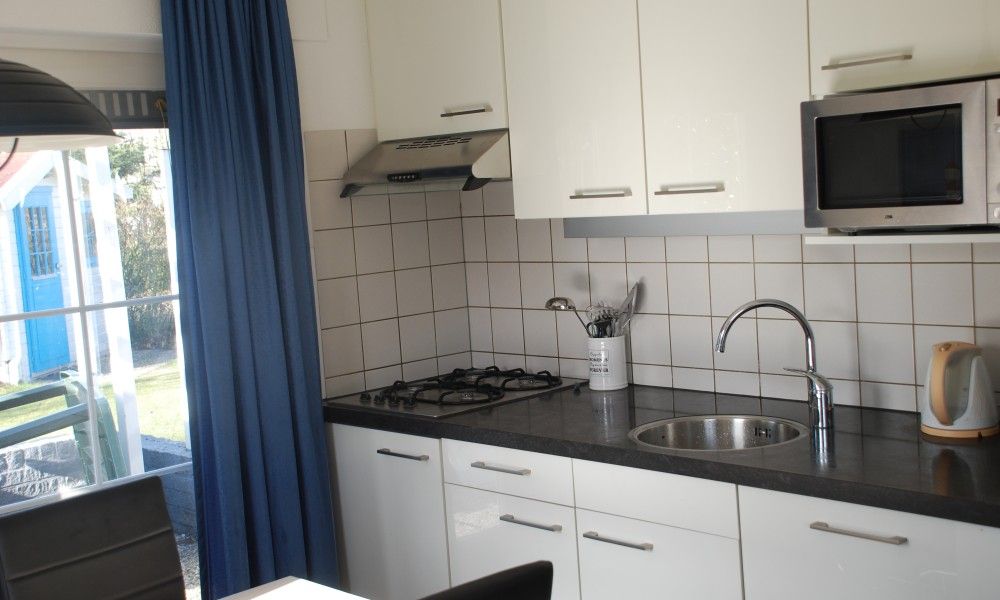 Modern kitchen in Krim 661 with sauna, Stuha, and BBQ, a bungalow in De Cocksdorp, Texel, Wadden Islands, overlooking the garden.