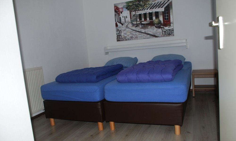 Comfortable bedroom in Krim 661 with sauna, Stuha, and BBQ, a bungalow in De Cocksdorp, Texel, with modern furnishings and art on the walls.