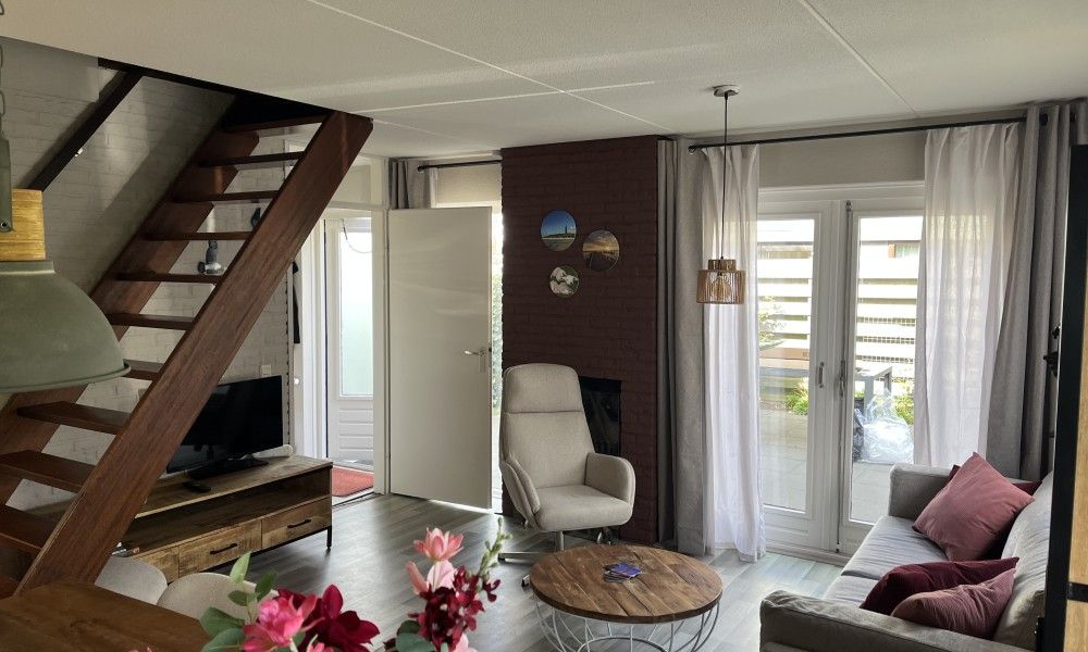 Gezellige woonkamer van TXL Huisje 299 in De Cocksdorp, Texel met comfortabele zithoek en toegang tot het terras.