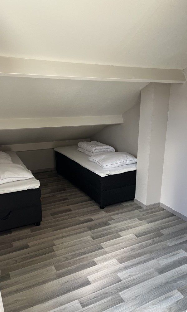 Gezellige slaapkamer in TXL Huisje 299, een vakantiehuis in De Cocksdorp op Texel, Waddeneilanden, met comfortabele bedden onder een schuin dak.