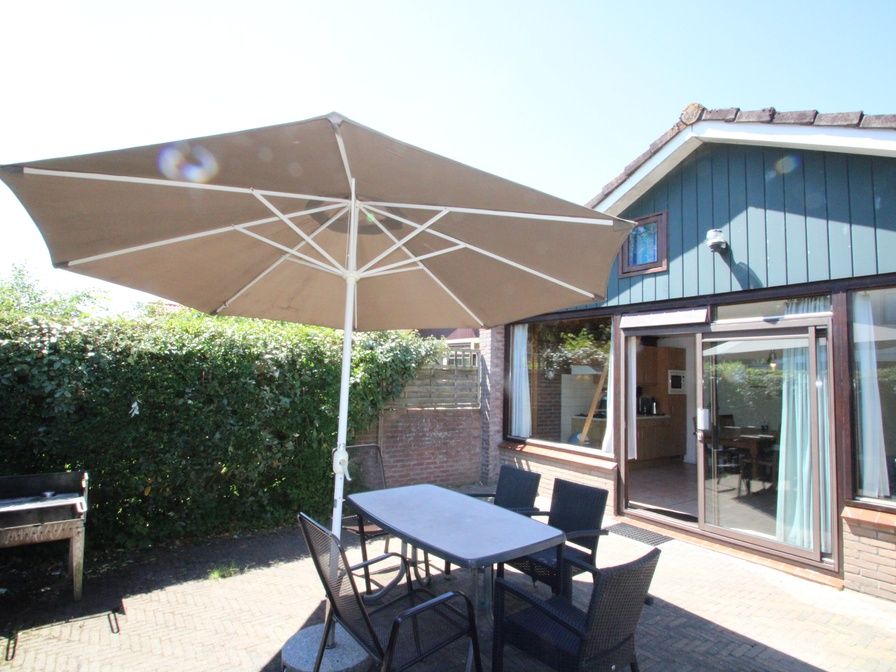 Geniet van het zonnige terras bij Vakantiehuis Slufterhoek 114 in De Cocksdorp, Texel, met comfortabele zitplaatsen en parasol.
