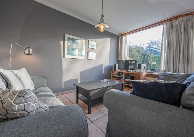 Lichte woonkamer met grote ramen in Vakantiehuis Slufterhoek 114, De Cocksdorp, Texel, biedt uitzicht op de tuin.