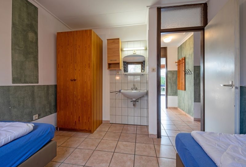 Functionele slaapkamer in Vakantiehuis Slufterhoek 114, De Cocksdorp, Texel, met wastafel en handige opbergruimte.