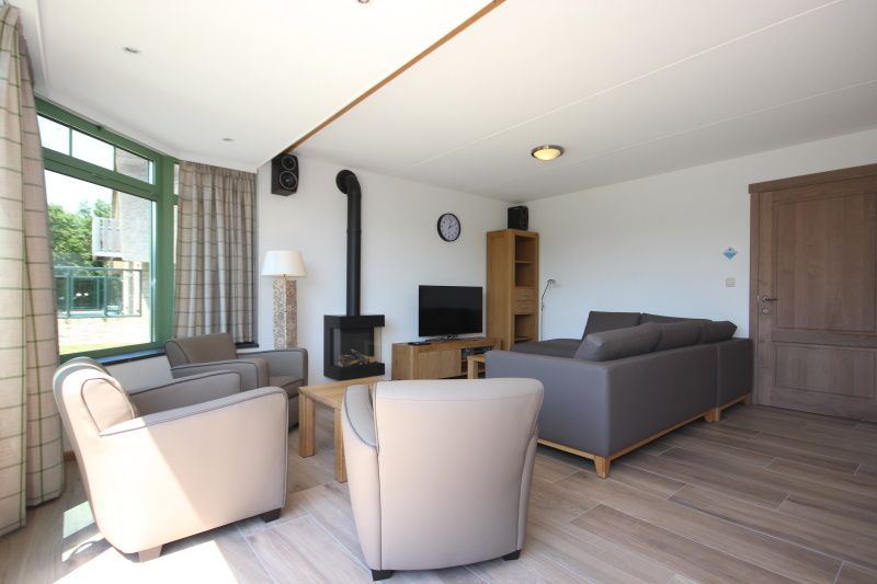 Cozy living room in Villa De Witte Hoek 138 conservatory, De Cocksdorp Texel, vacation home with comfortable sitting area and lots of natural light.