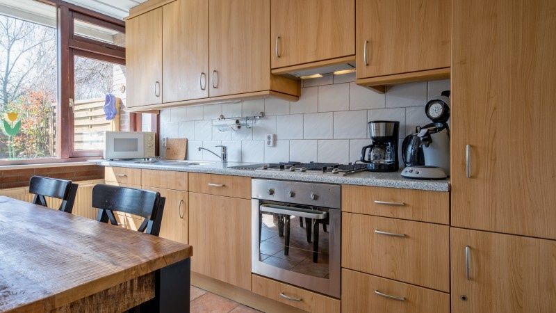 Moderne keuken in Vakantiehuis Slufterhoek 100, De Cocksdorp, Texel met uitzicht op de tuin.