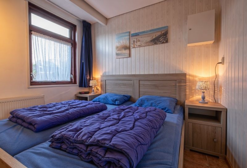 Sfeervolle slaapkamer in Vakantiehuis Slufterhoek 100, De Cocksdorp, Texel met tweepersoonsbed.