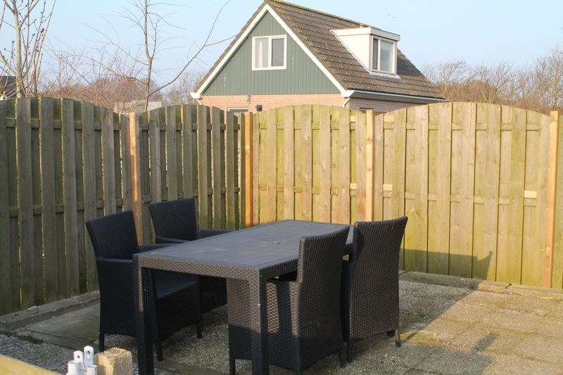 Gezellig terras bij Onder de vuurtoren 115, vakantiehuis in De Cocksdorp, Texel met houten schutting en tuinmeubilair.