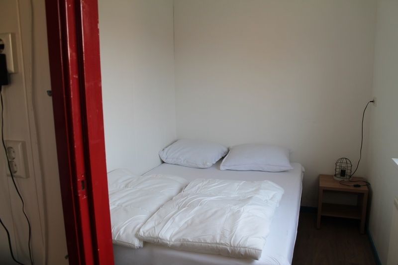 Sfeervolle slaapkamer in Onder de vuurtoren 115, Texel, De Cocksdorp met comfortabel tweepersoonsbed en nachtkastje.