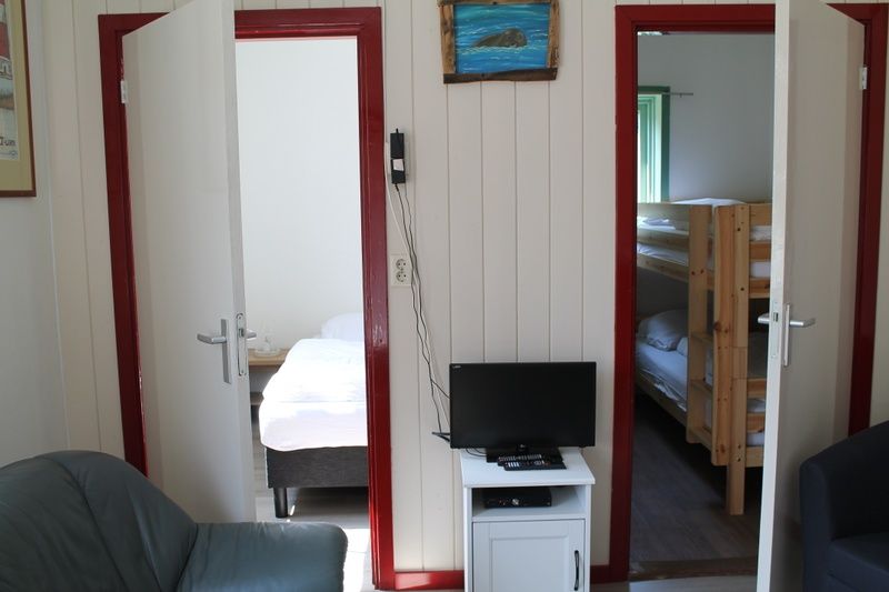 Interieur vakantiehuis Onder de vuurtoren 115, Texel met toegang tot slaapkamers en woonkamer met televisie.