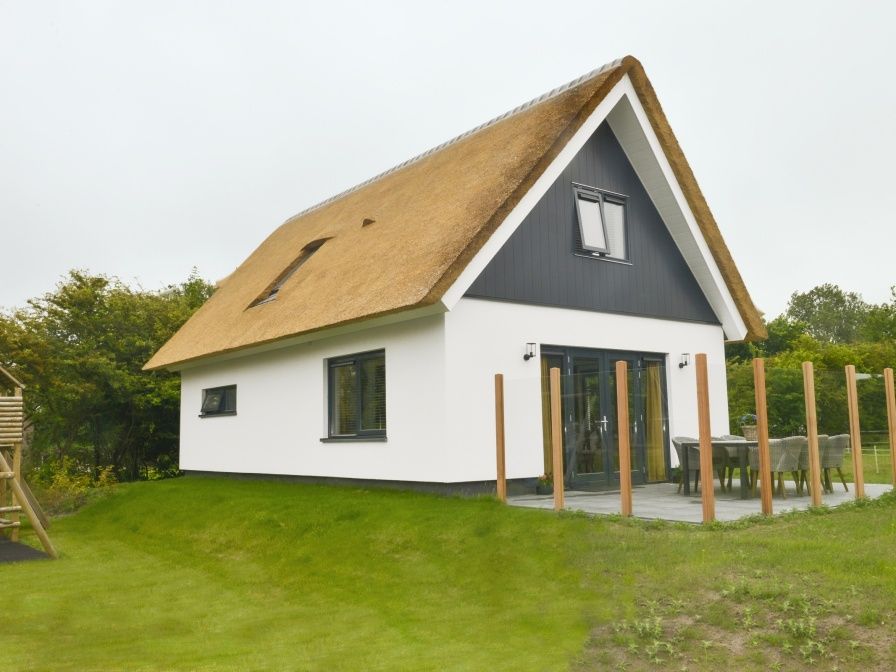 De Postschipper vakantiehuis met rieten dak in De Cocksdorp, Texel, omringd door groen.