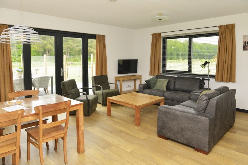 Gezellige woonkamer van De Postschipper vakantiehuis in De Cocksdorp, Texel, met uitzicht op de tuin.