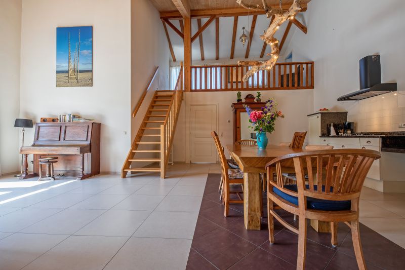 Open leefruimte met houten trap in Vakantiehuis Paal 86, De Cocksdorp, Texel.