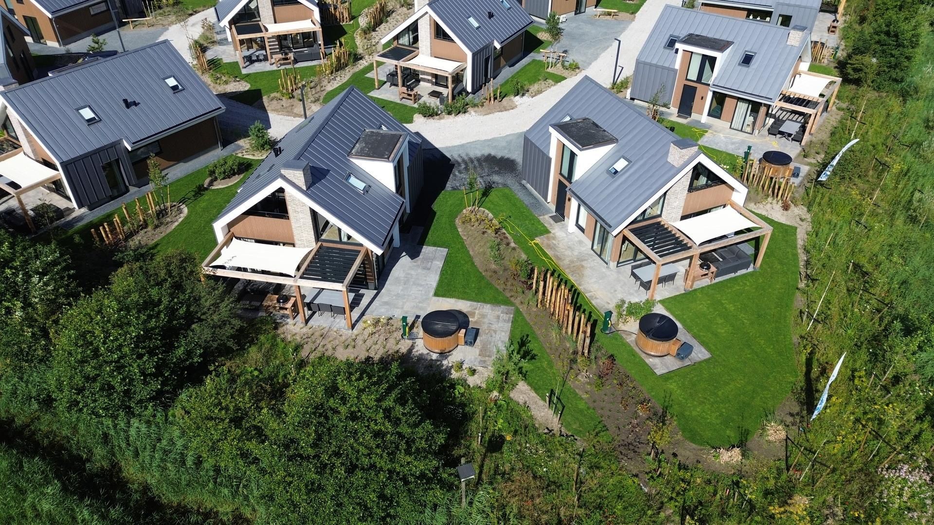 Luchtfoto van Duinvilla Wellness 5, een luxe vakantiehuis in De Cocksdorp, Texel, omgeven door groene tuinen en moderne architectuur.