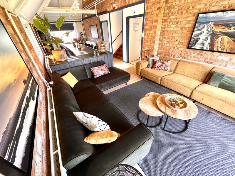 Stijlvolle woonkamer in Noorderwind accommodatie, De Cocksdorp, Texel met moderne meubels en kunst aan de muur.