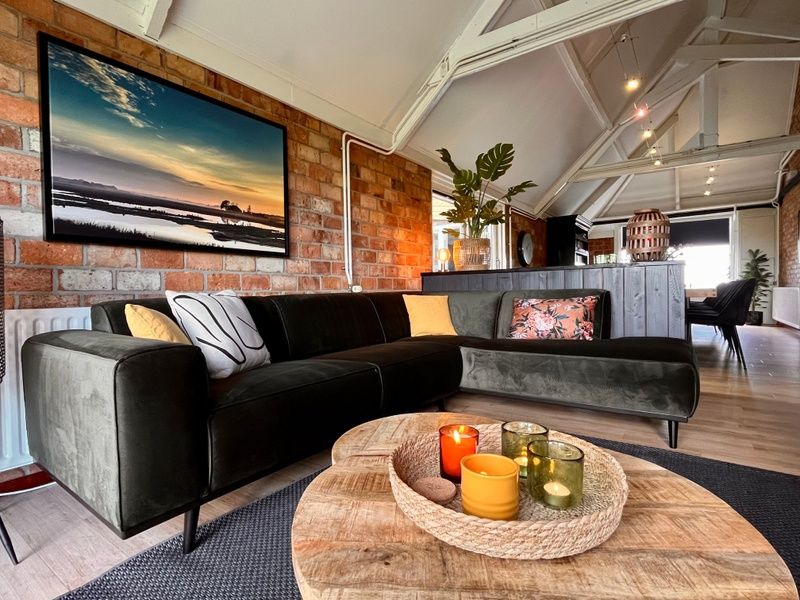Sfeervolle woonkamer van Noorderwind, De Cocksdorp, Texel met moderne bank en decoratieve kaarsen.