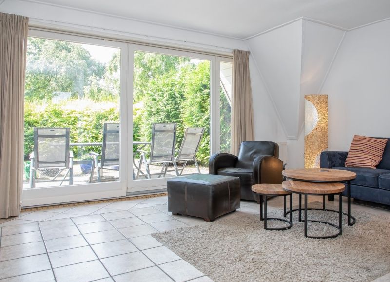 Ruime zithoek met uitzicht op de tuin in Vakantiehuis Slufterduin 076, De Cocksdorp, Texel. Geniet van de natuur op de Waddeneilanden.