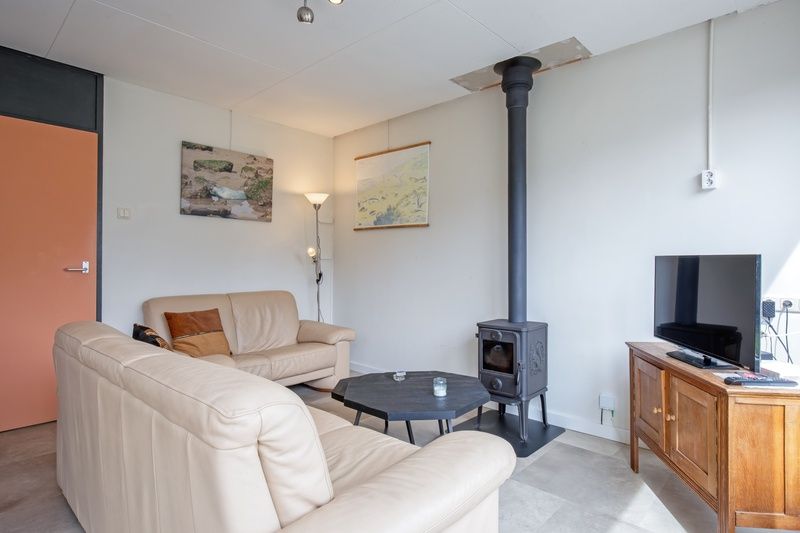 Comfortabele woonkamer van Vakantiehuis Slufterhoek 118 in Texel met houtkachel en moderne inrichting.