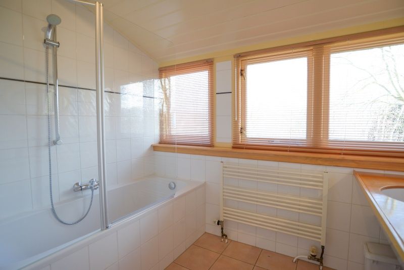 Badkamer met bad en douche in De Velduil vakantiehuis, Texel.