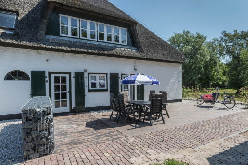 Zonnig terras van vakantiehuis Type W in De Cocksdorp Texel met tuinmeubilair en parasol.