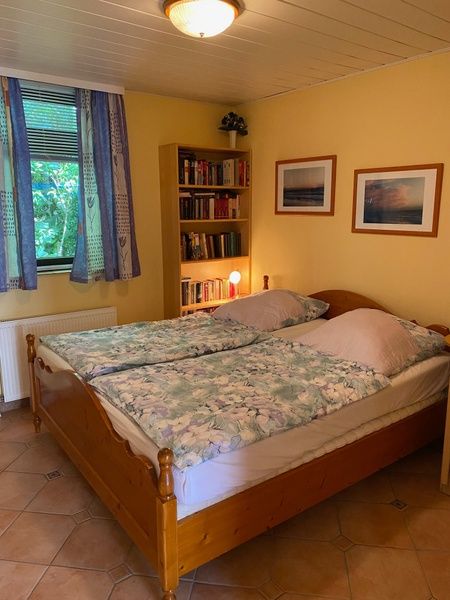 Slaapkamer in Vakantiehuis Slufterhoek 128, De Cocksdorp, Texel met tweepersoonsbed en boekenplank.