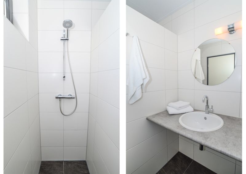Stijlvolle badkamer in Vakantiehuis 34A, De Cocksdorp, Texel met moderne douche en wastafel.