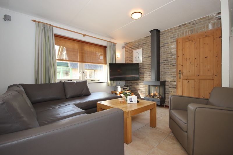Cozy living room in Villa De Witte Hoek conservatory, vacation home on Texel, with comfortable seating area.