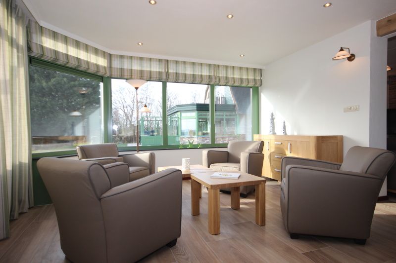 Light seating area in Villa De Witte Hoek conservatory, De Cocksdorp, Texel, overlooking the garden.