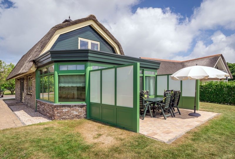 Outdoor terrace with dining table in Villa De Witte Hoek conservatory, vacation home in De Cocksdorp, Texel.