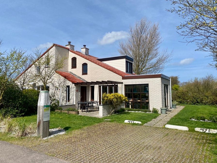 Vakantiehuis D 491 in De Cocksdorp, Texel met zonnige veranda en groene omgeving, ideaal voor een ontspannen verblijf op de Waddeneilanden.