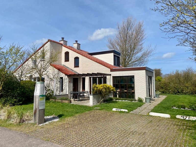 Vakantiehuis D 491 in De Cocksdorp, Texel, omgeven door groene natuur, met een uitnodigend terras voor een ontspannen verblijf op de Waddeneilanden.