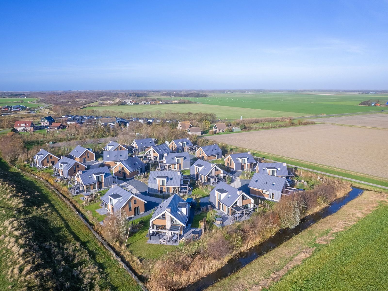 Luftaufnahme eines freistehenden Hauses in De Cocksdorp, Texel, umgeben von grnen Feldern und ruhiger Natur auf den Watteninseln.