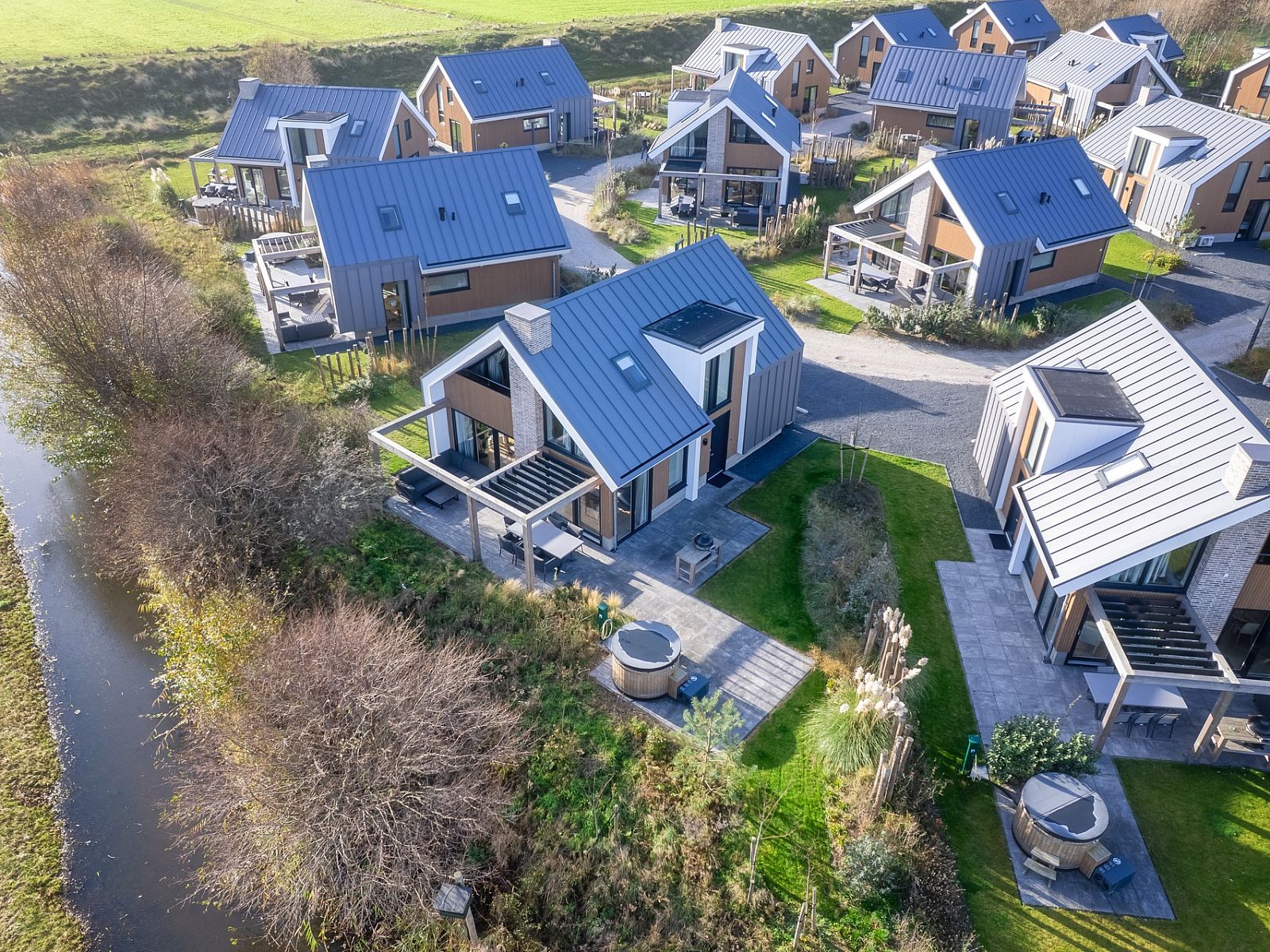 Luftaufnahme eines freistehenden Hauses in De Cocksdorp, Texel, umgeben von Natur und modernen Ferienhusern auf den Watteninseln.