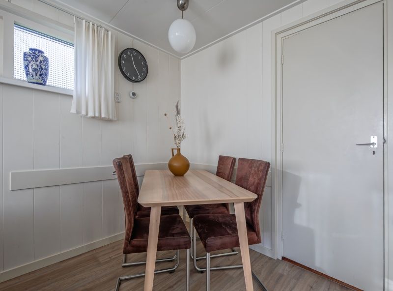 Essecke im Ferienhaus Kikkertstraat 60, De Cocksdorp, Texel mit stilvollem Holztisch und Stuehlen.