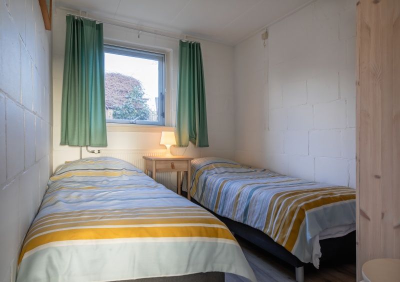 Schlafzimmer im Ferienhaus Kikkertstraat 60, De Cocksdorp, Texel mit zwei Einzelbetten und frischem Look.