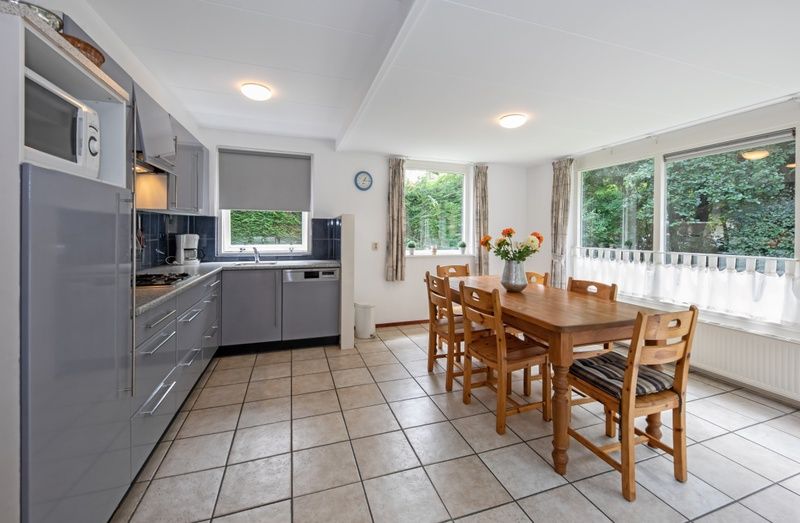 Esszimmer und Kueche des Ferienhauses Slufterduin 098, De Cocksdorp, Texel mit grossen Fenstern.