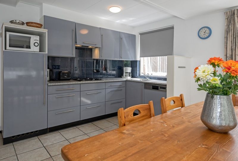 Kueche und Esszimmer im Ferienhaus Slufterduin 098, De Cocksdorp, Texel mit Holztisch.