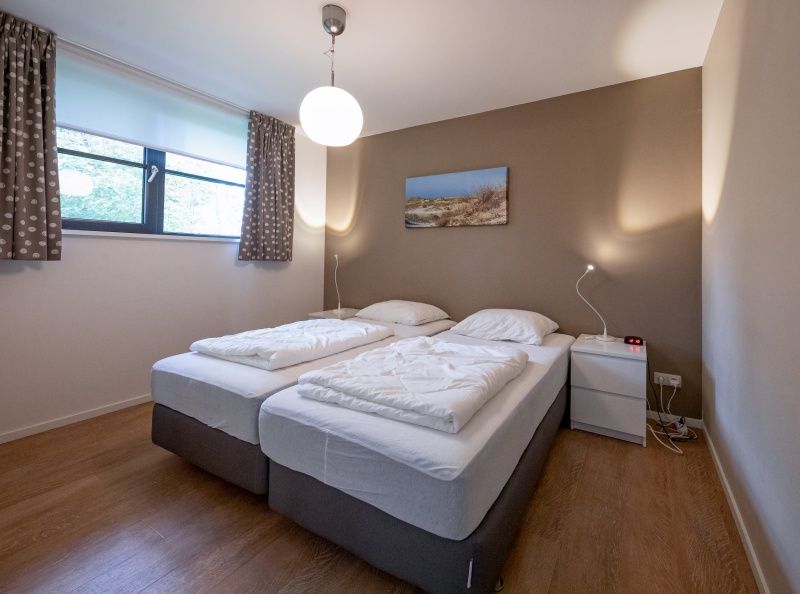 Comfortable bedroom in Holiday home Slufteroord 240, Texel with two single beds and atmospheric lighting.