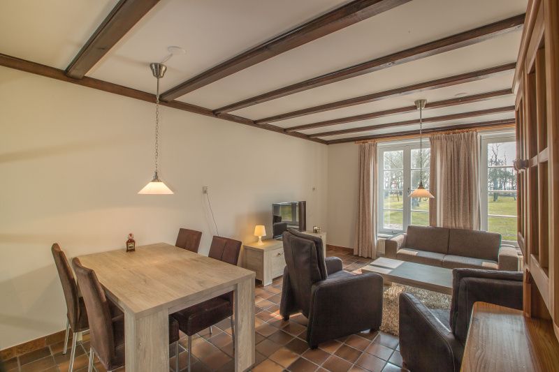 Gezellige woonkamer in Type R vakantiehuis, De Cocksdorp, Texel, met grote ramen en comfortabele zitplaatsen.