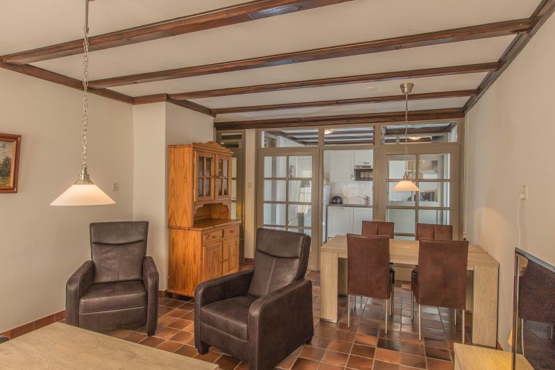 Eet- en zitgedeelte in Type R vakantiewoning, De Cocksdorp, Texel, met houten meubels en warme sfeer.