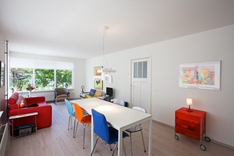 Lichte woonkamer in Bungalow Schelpenoord - Vakantiehuis De Oester, De Cocksdorp, Texel, met kleurrijke stoelen en moderne inrichting.