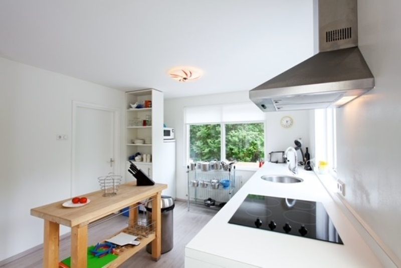 Moderne keuken in Bungalow Schelpenoord - Vakantiehuis De Oester, De Cocksdorp, Texel, met kookplaat en uitzicht op de tuin.