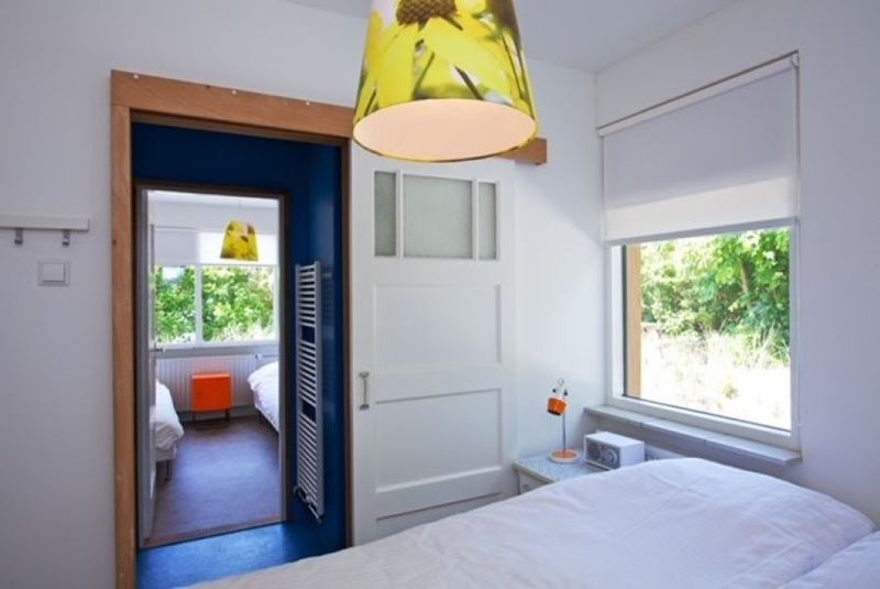 Slaapkamer in Bungalow Schelpenoord - Vakantiehuis De Oester, De Cocksdorp, Texel, met grote ramen en een frisse uitstraling.