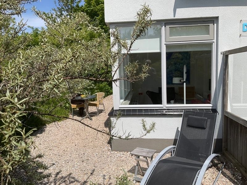 Zonnig hoekje met ligstoel bij Bungalow Schelpenoord - Vakantiehuis De Oester, De Cocksdorp, Texel, ideaal voor ontspanning.